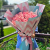 Hand‑tied bouquet of blush pink roses wrapped in pastel teal and pink patterned paper
