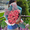 Hand‑tied bouquet of blush pink roses wrapped in pastel teal and pink patterned paper