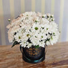 Black Bloom de Fleur hatbox with dark green ribbon, overflowing with white chrysanthemum daisies with green centers.
