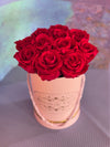 Light pink Bloom de Fleur hatbox with rope handles holding a dozen deep red roses.